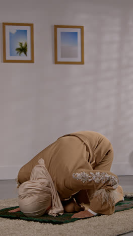 Vertikales-Video-Einer-Muslimischen-Frau-Mit-Hijab,-Die-Zu-Hause-Kniend-Auf-Einer-Gebetsmatte-Betet-2